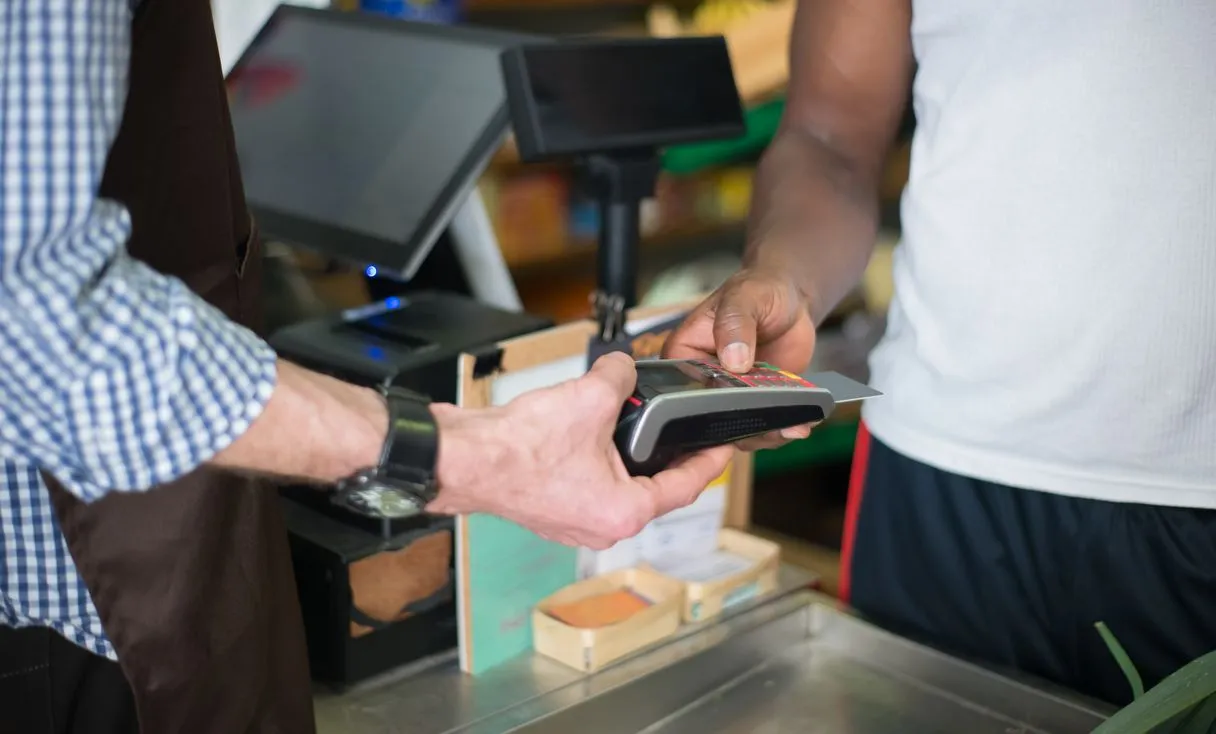 Cliente pagando no balcão de uma loja, cena representando: Cliente Não Pagou o Conserto? Como Cobrar Sem Perder o Cliente