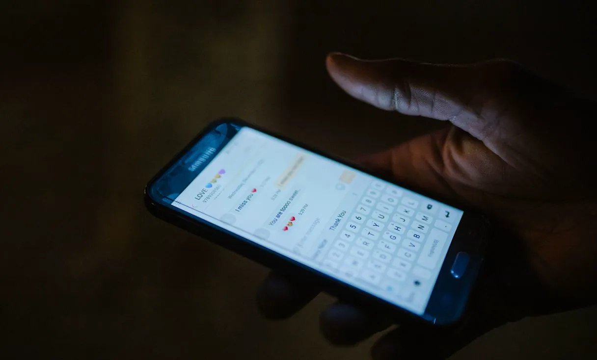 Close de mão segurando celular com conversa aberta, como na aprovação de orçamento