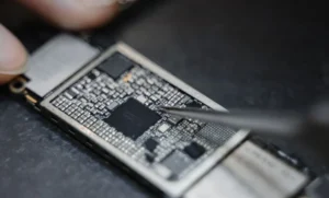 Mão trabalhando em placa de smartphone na bancada representando: Automação no WhatsApp da assistência: passos práticos