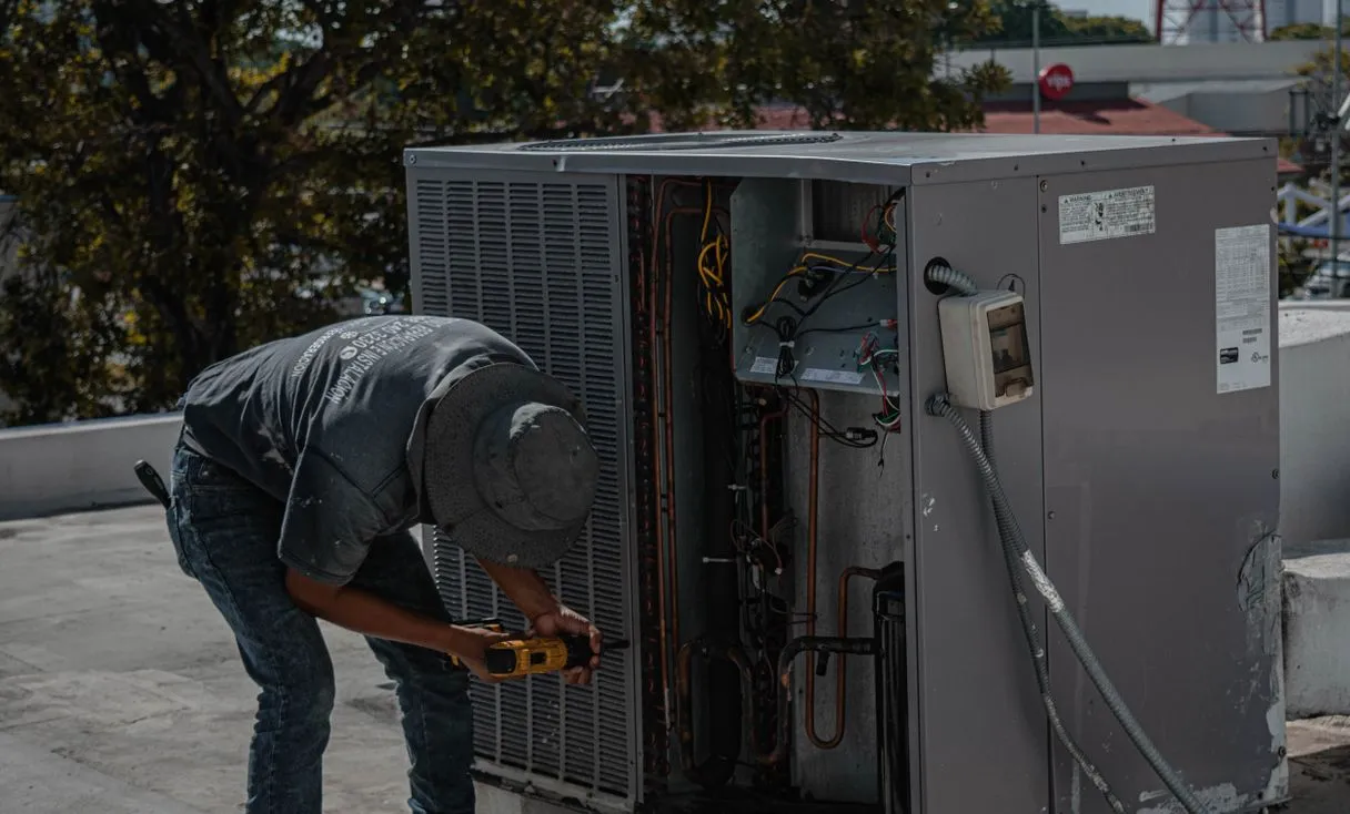 Técnico instalando ar-condicionado em área externa representando: OS como contrato simples na refrigeração: como fazer