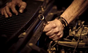 Mãos de mecânico ajustando motor na oficina, representando: Oficina: veículo pronto e o cliente não busca — diária, termo e como avisar